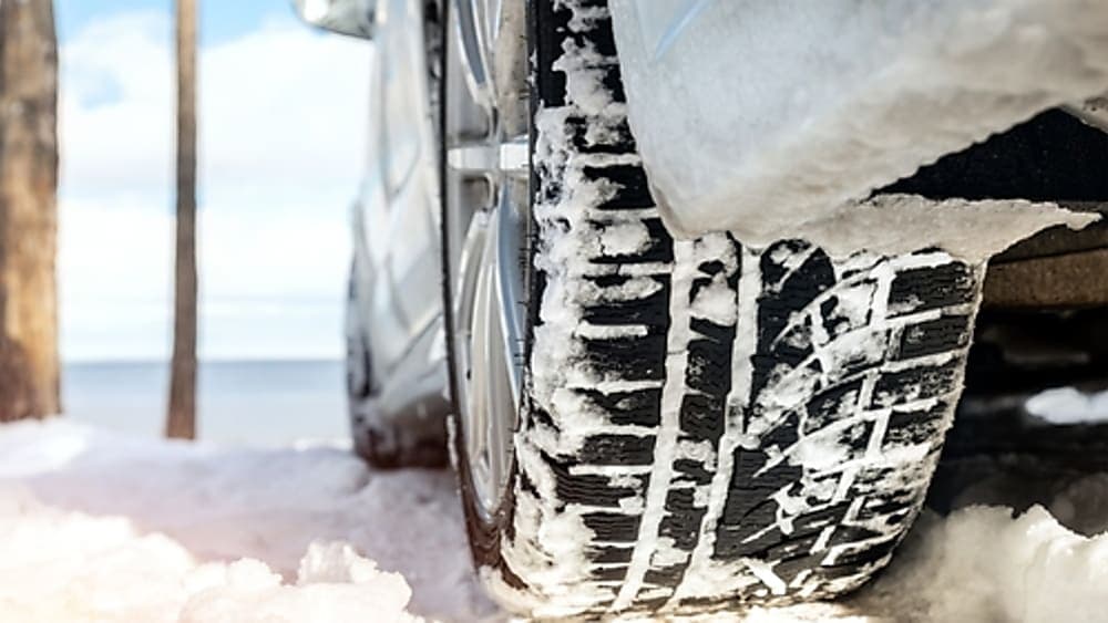 Close-up of a winter tire driving safely down a snowy dirt road